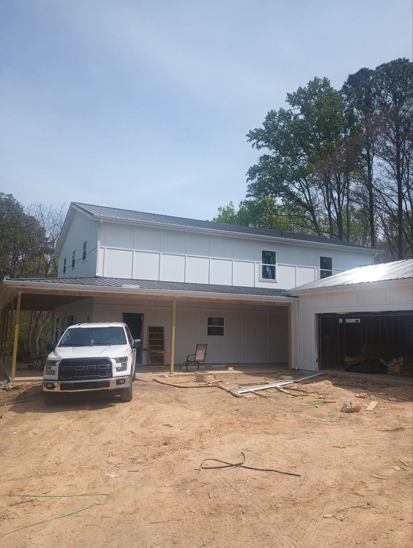 Finished exterior with white board and batten siding, black metal roof, and porch