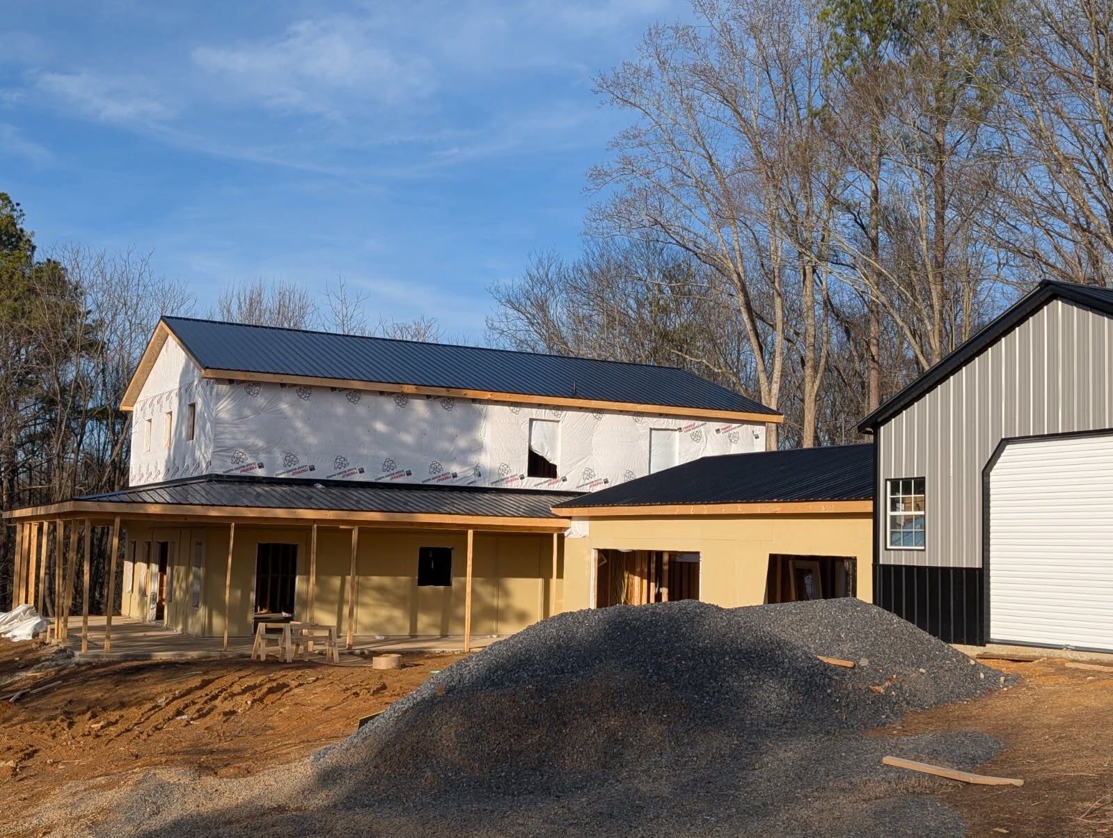 Completed custom barn with metal roof, board and batten siding, and covered porch