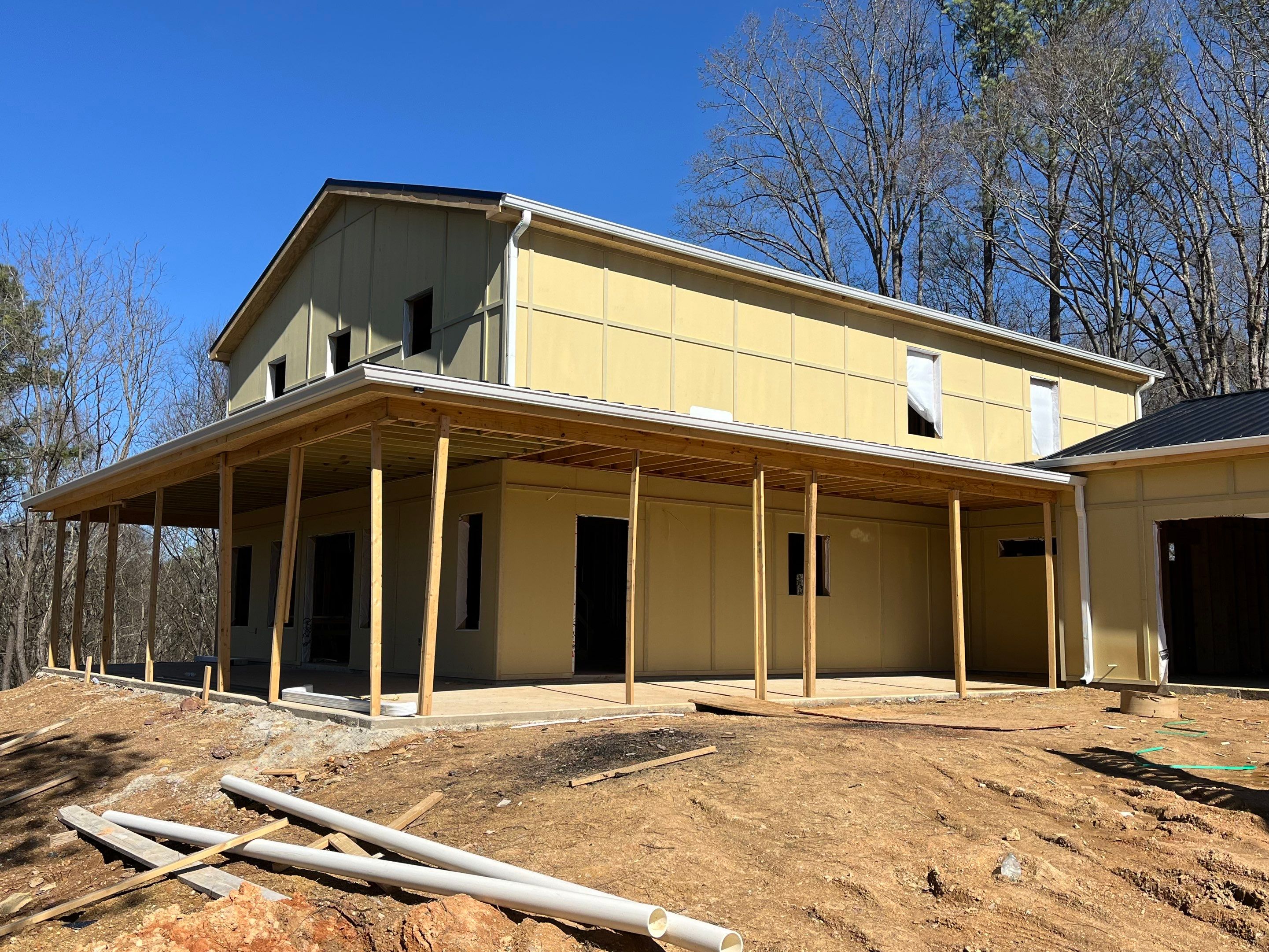 Exterior under construction with raw siding and porch framing